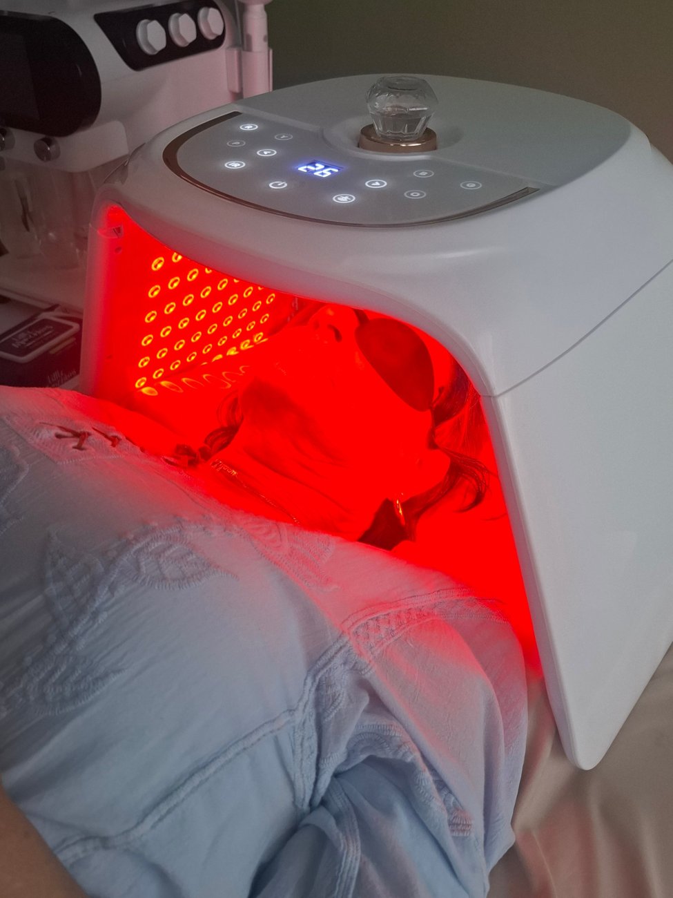 A client under a red LED light therapy panel
